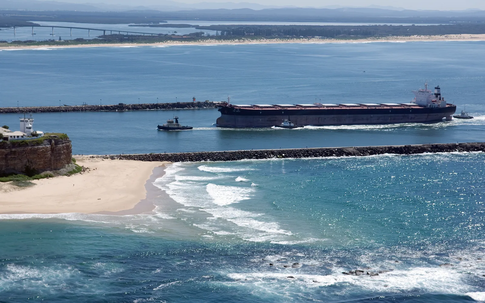 A laden bulk carrier and tug entering the port of Newcastle, New South Wales